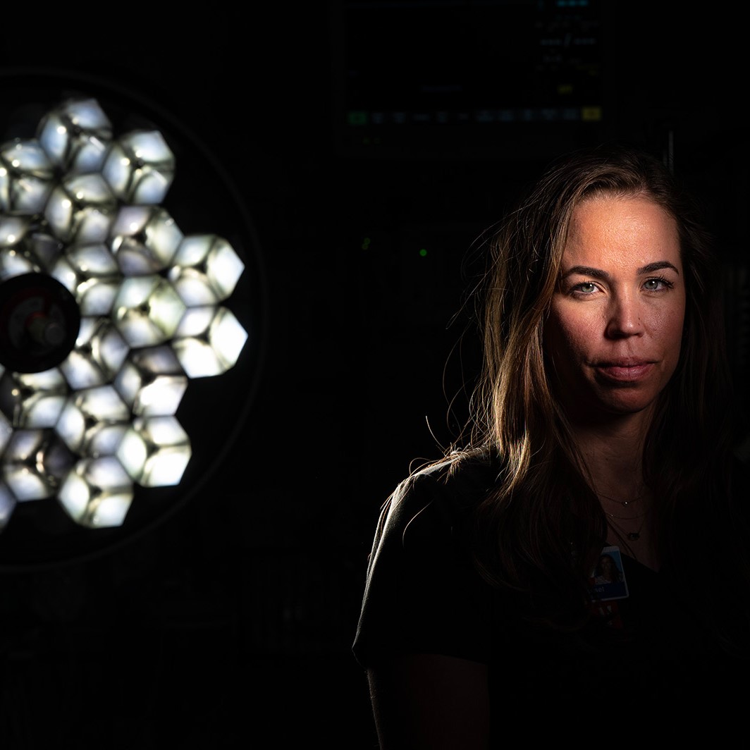 A woman poses for a photo in a dark room with a spotlight on her face