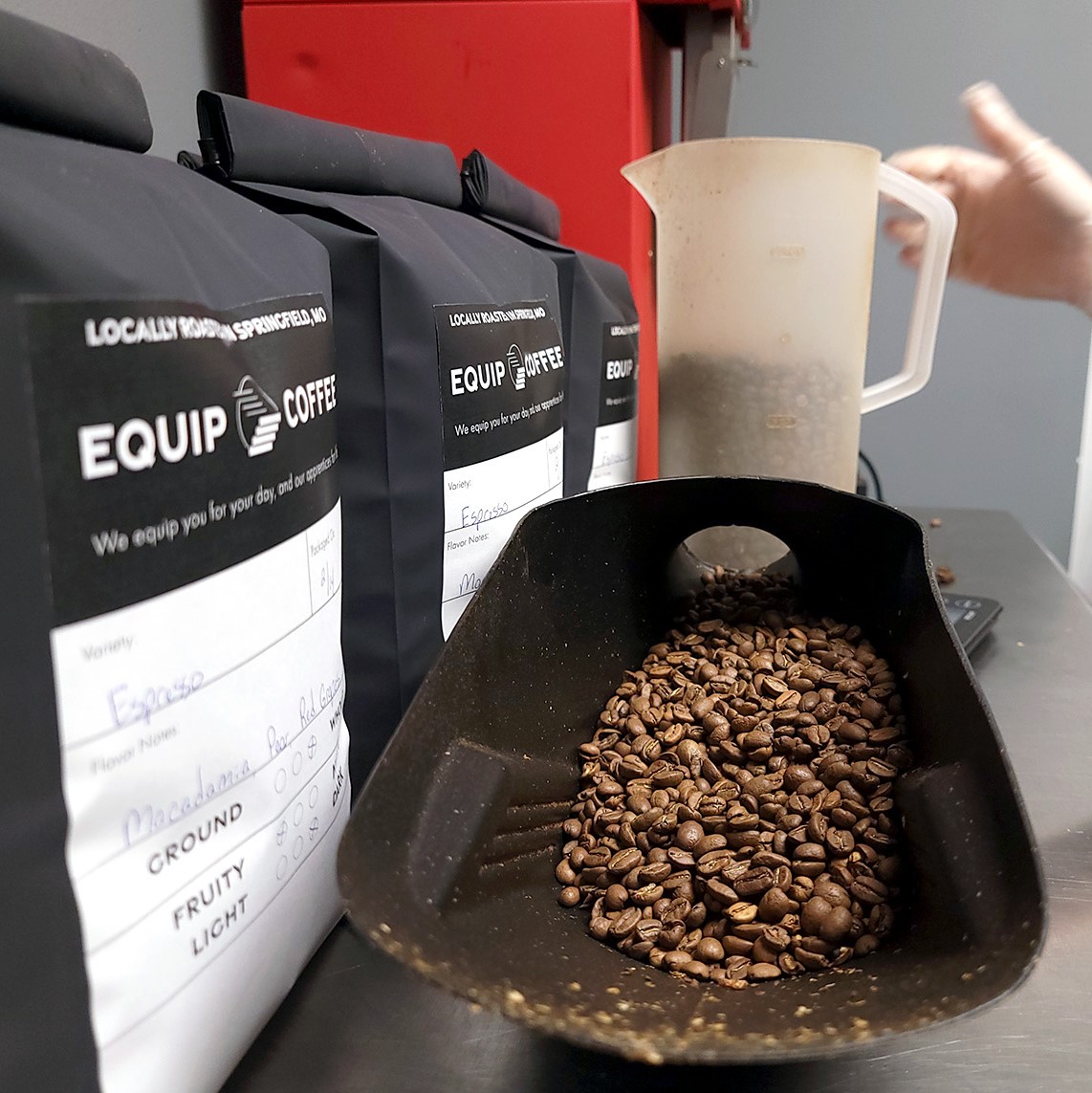 Coffee beans sit in a scale next to bags of Equip Coffee