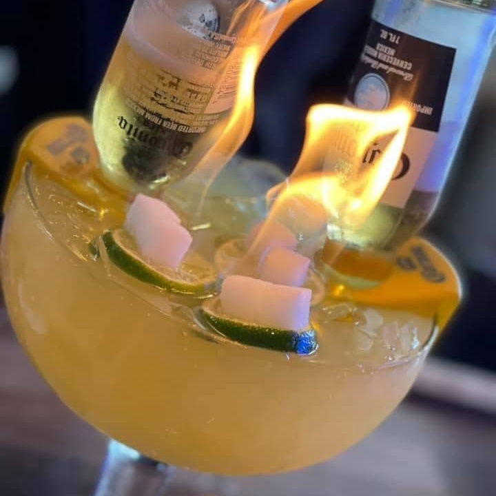 A flaming margarita, with two bottles of beer tipped upside down in it