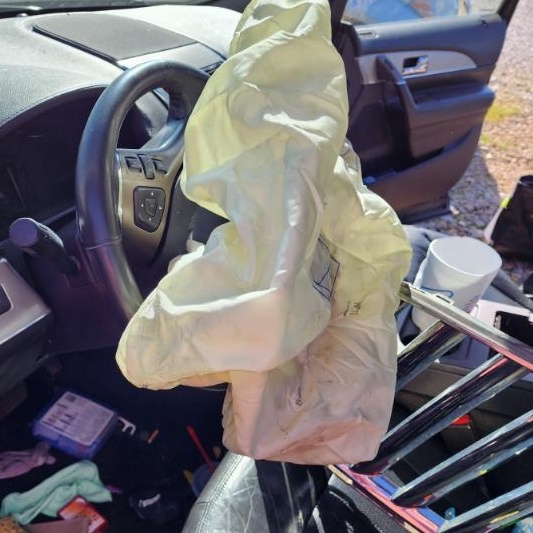 Interior photo of an SUV with a deflated airbag resting on the steering wheel