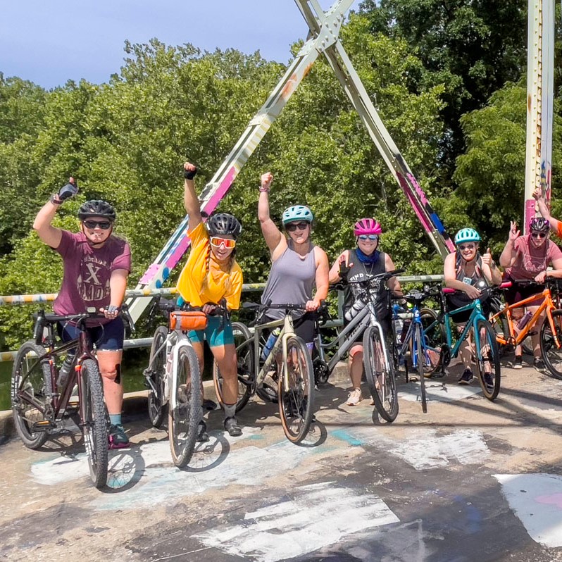 A group of women poses for a photo on a bridge during a group cycling ride