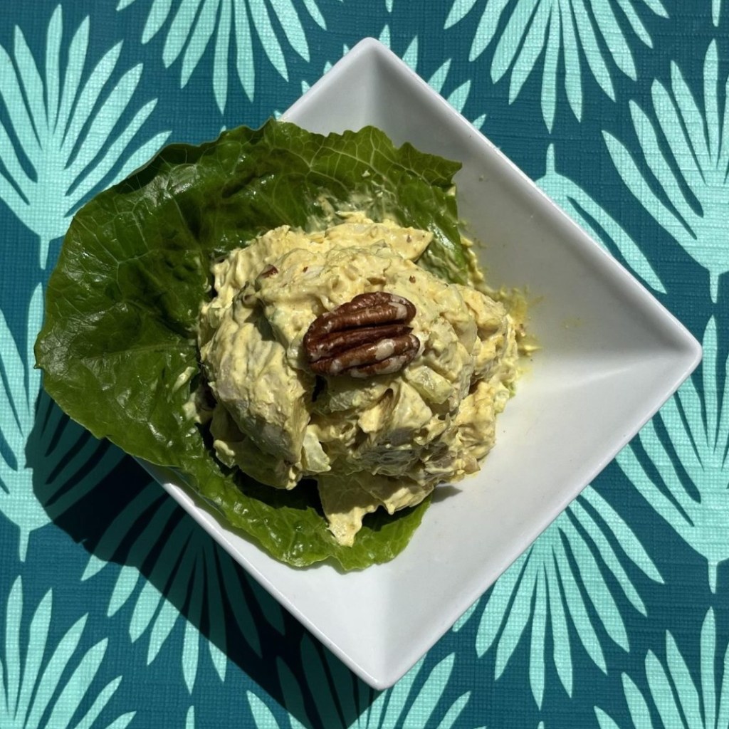 A dish of chicken salad sits on a blue-patterned tablecloth