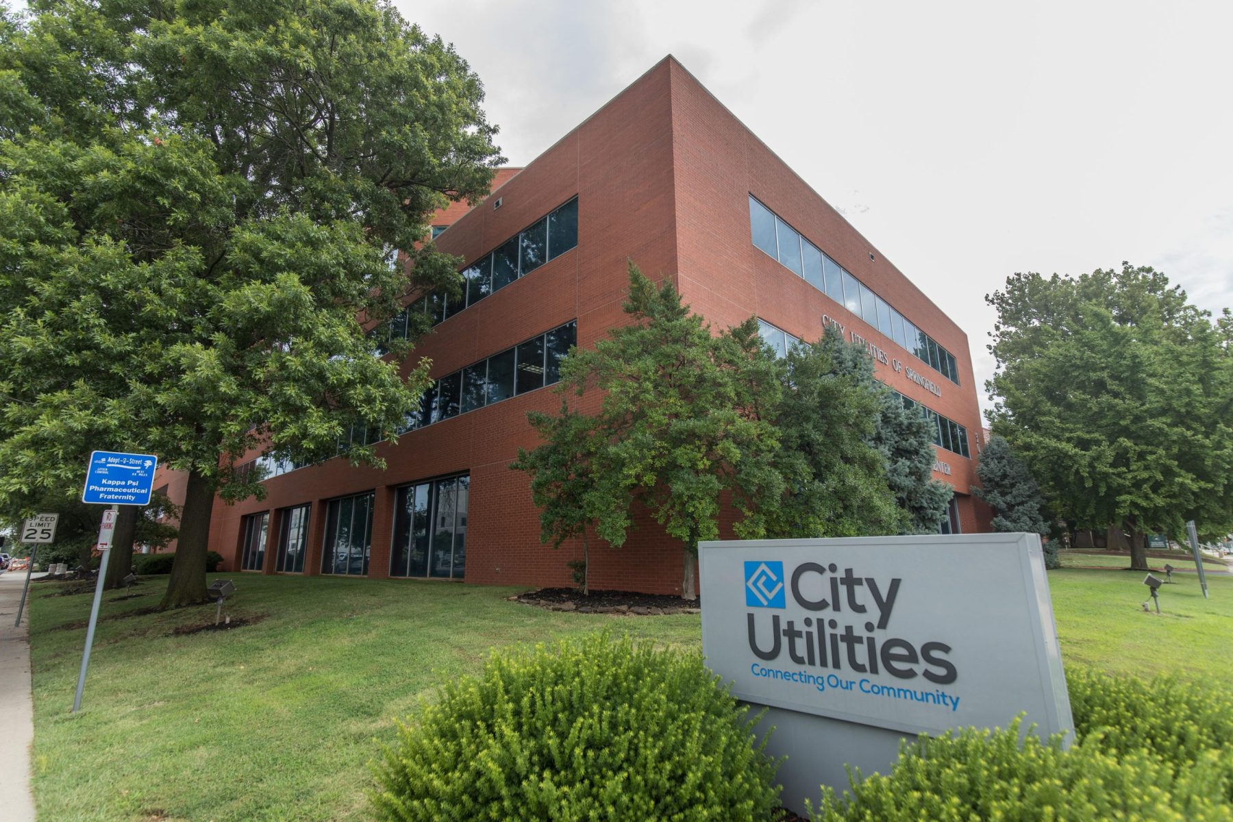 City Utilities with building and trees in the background on a cloudy spring day.