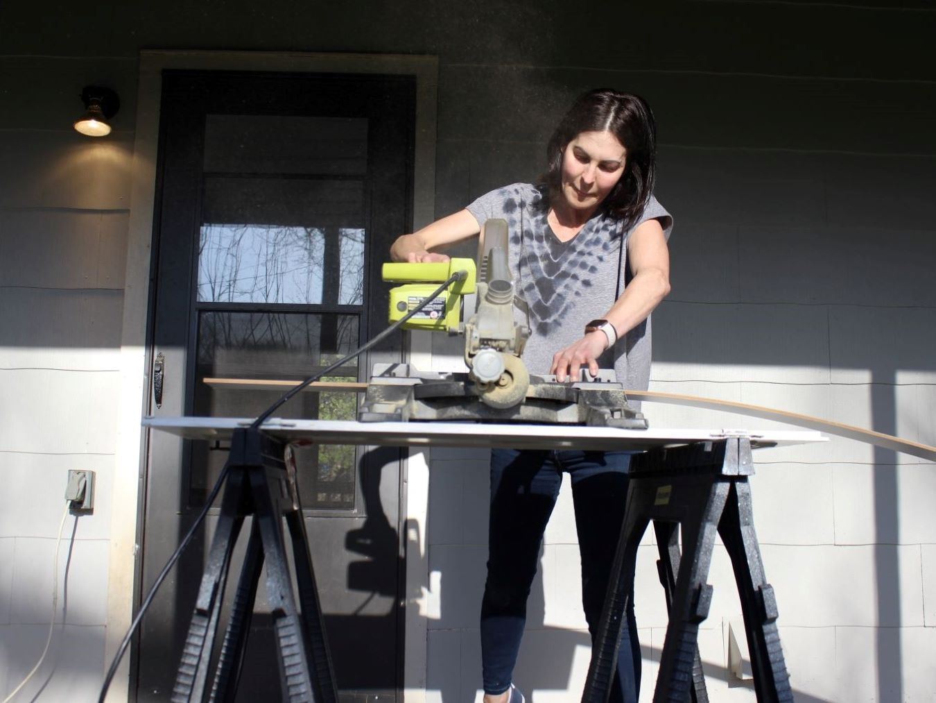 Former Springfield teacher Stephanie Reid works with a miter saw outside her vacation rental home.
