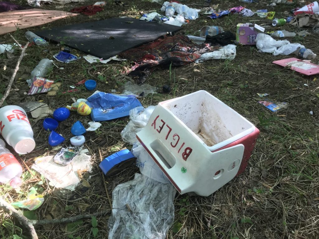 A cooler and pieces of trash are on the ground where homeless people used to camp in west Springfield.