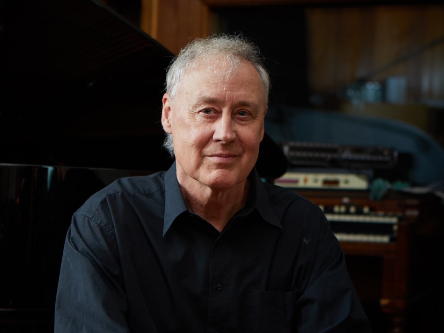 Singer Bruce Hornsby sits in front of a piano and organ
