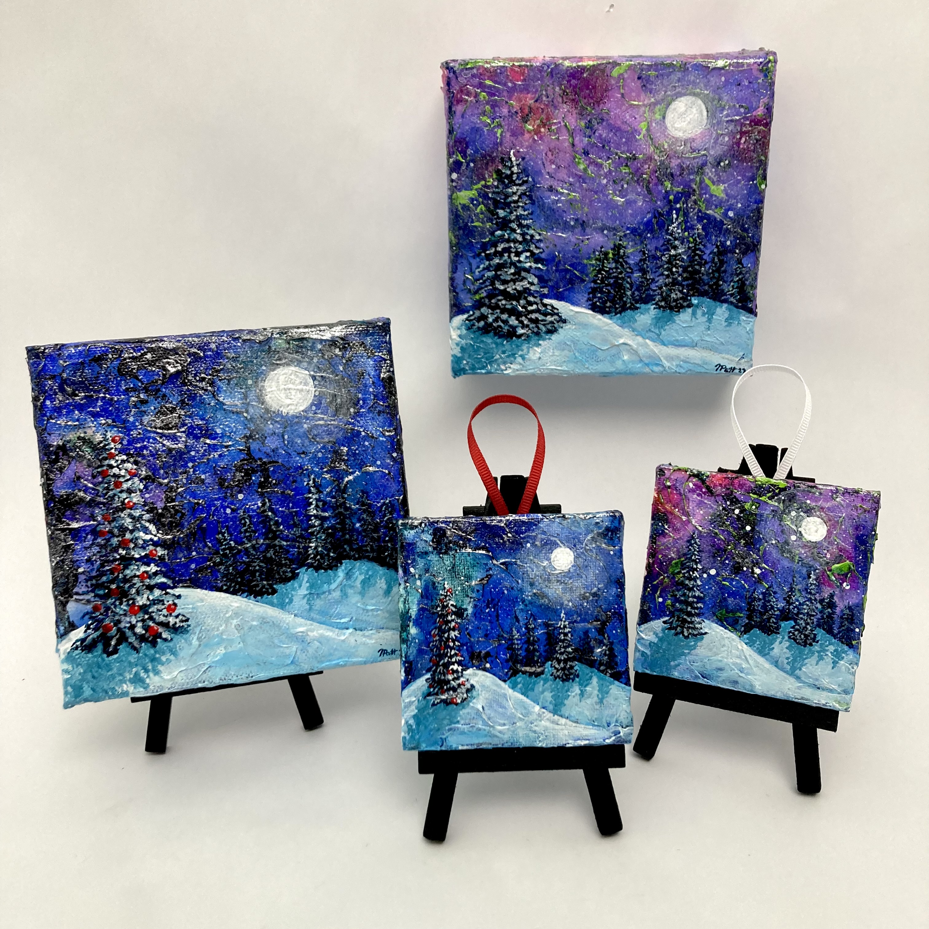 Four small canvases, featuring hand-painted winter scenes
