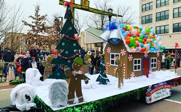 A Christmas parade float featuring a gingerbread house and people