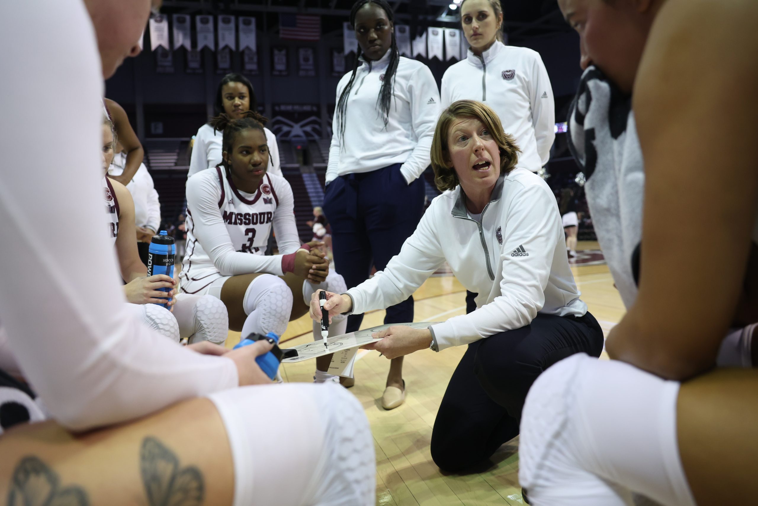 A basketball coach talks to her players in a huddle