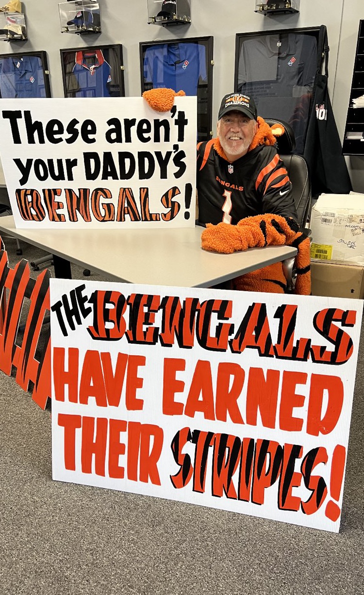 A man in a tiger costume holds signs that support the Cinicnnati Bengals football team