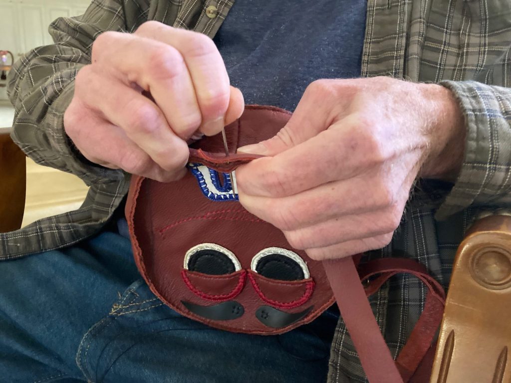 John Cottle puts the finishing touches on a hand-made leather bag.