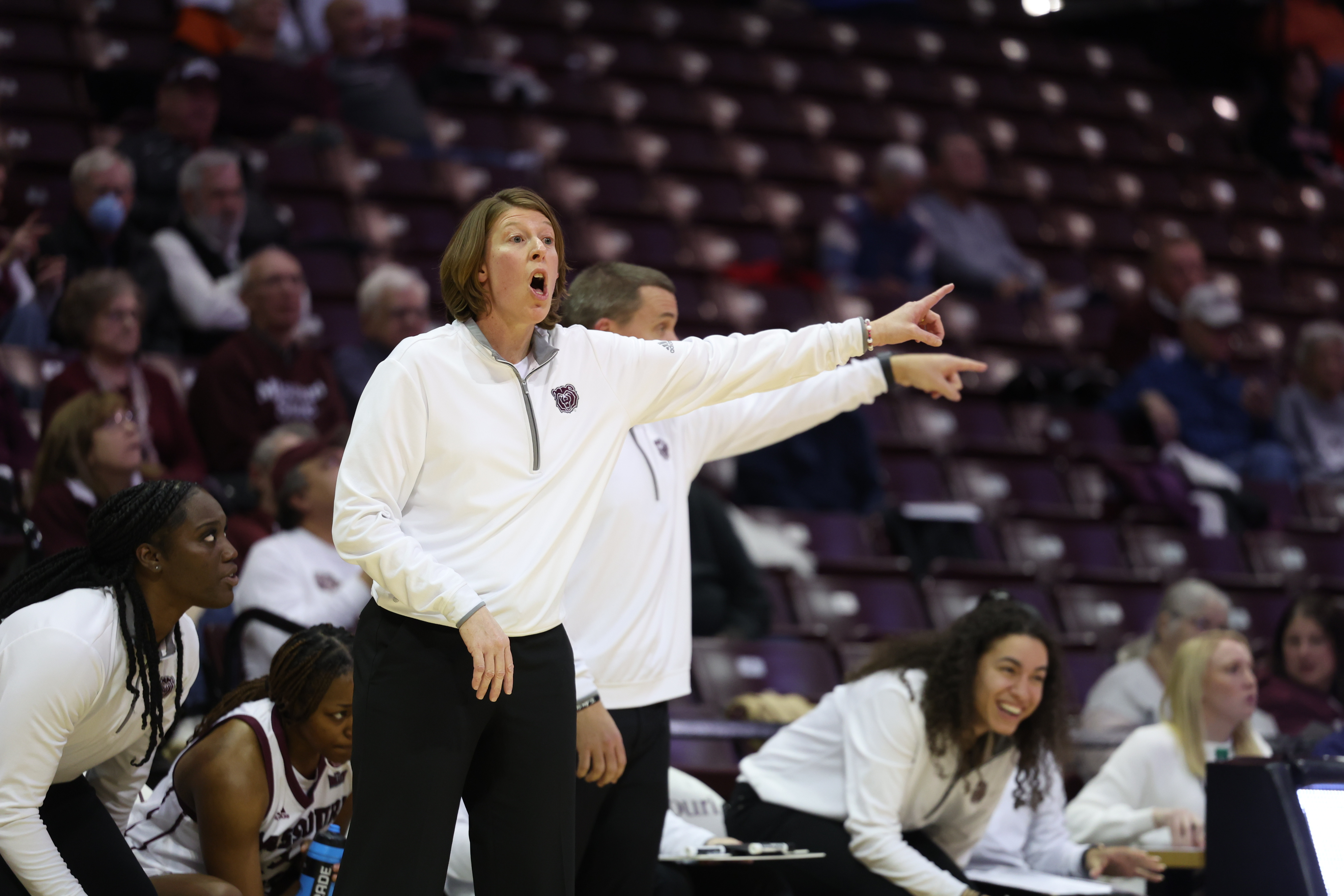 A female basketball coach shouts instructions to her team.