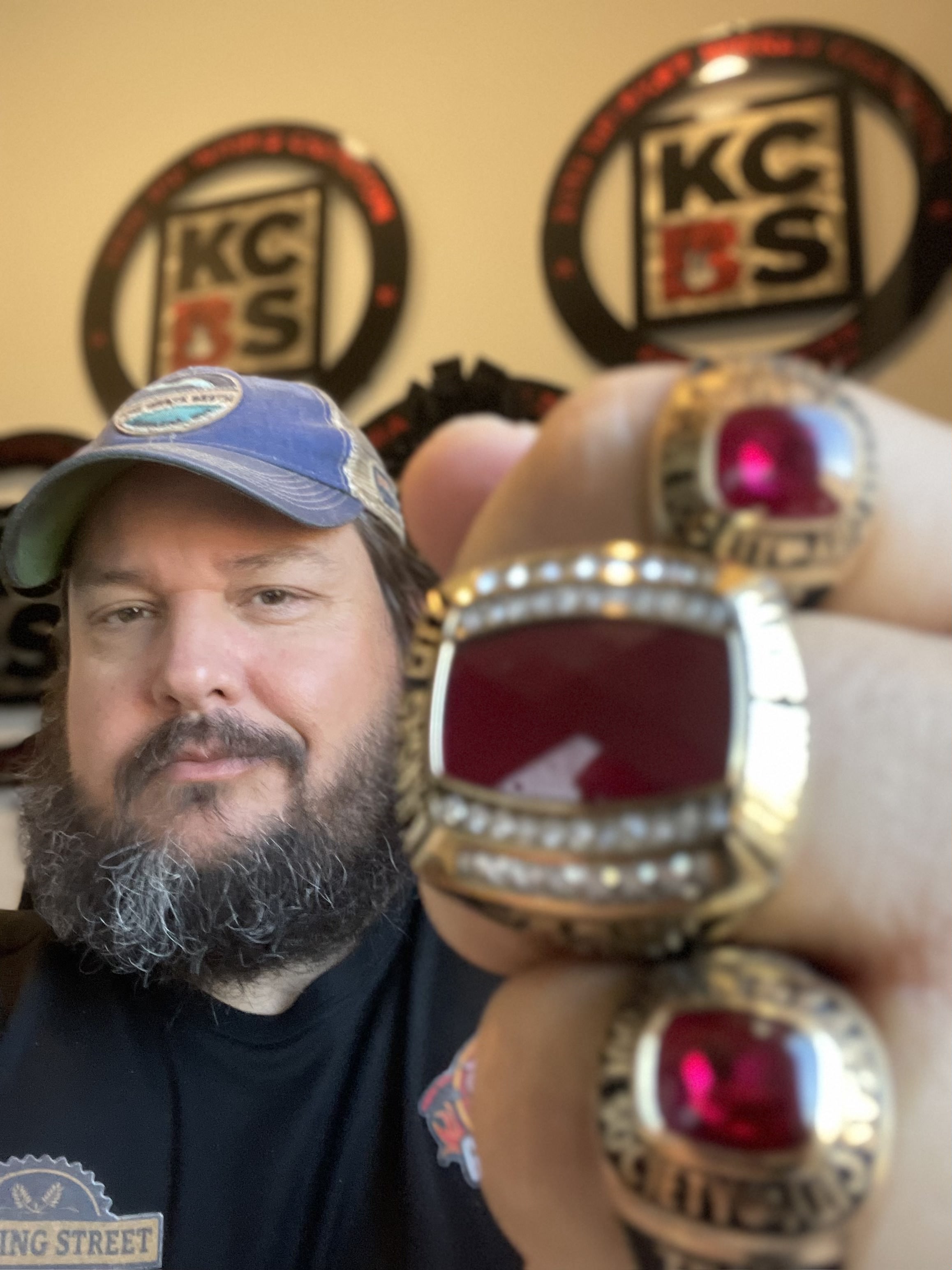 A man holds up three championship rings