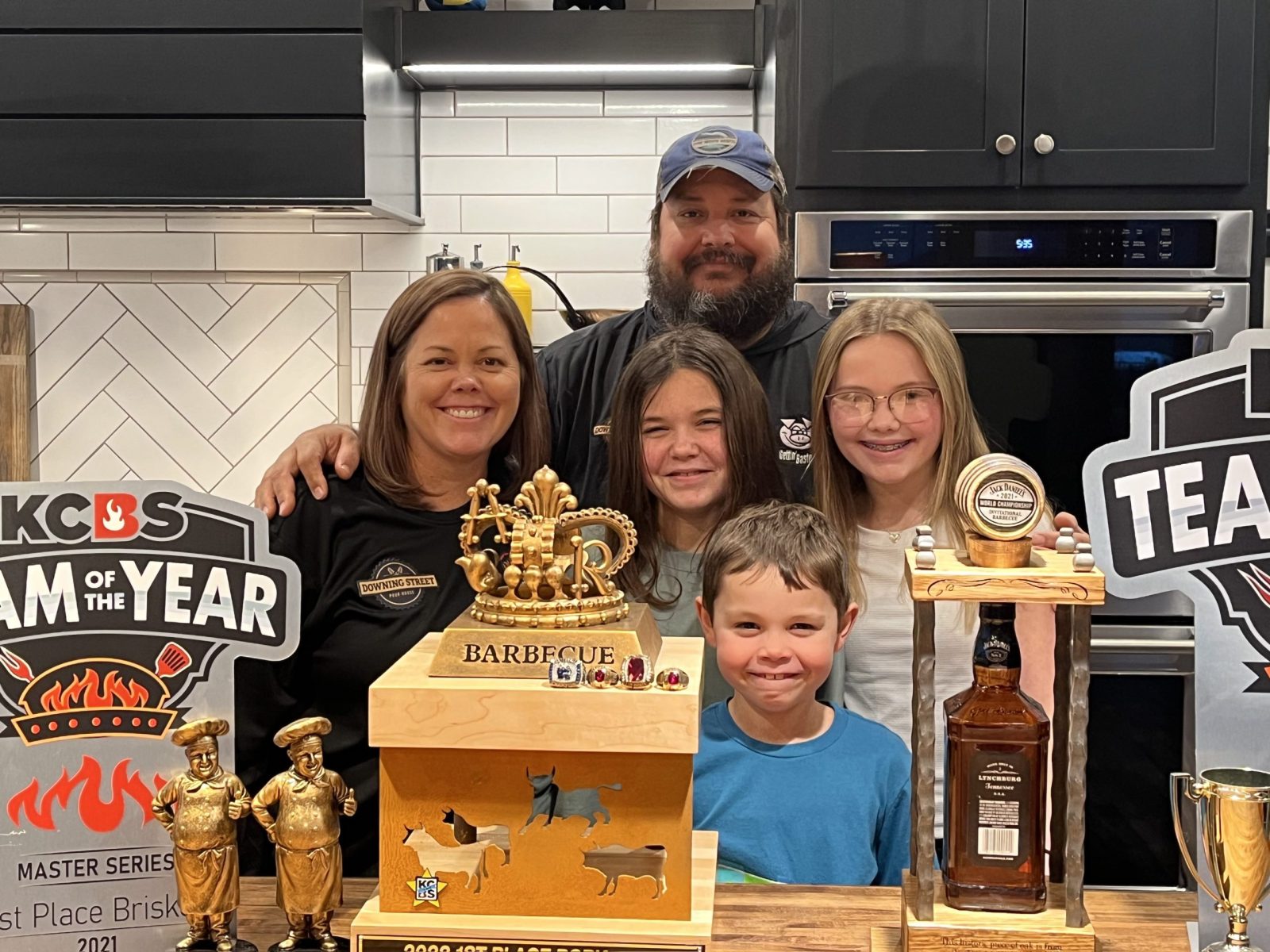 A family of five poses with trophies
