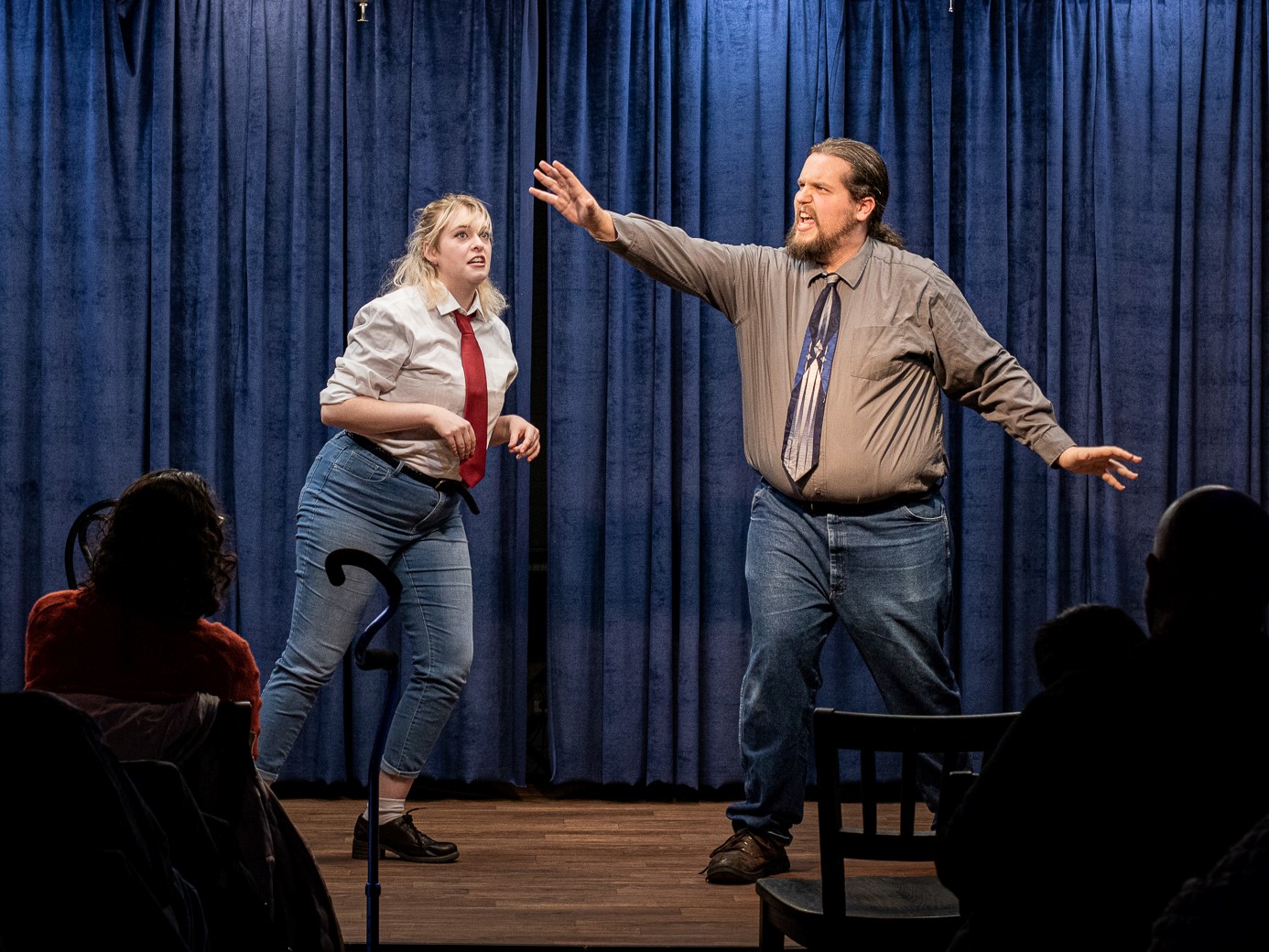 Two actors perform an improv scene on a stage