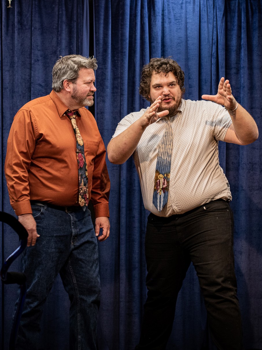Two actors perform an improv scene on a stage