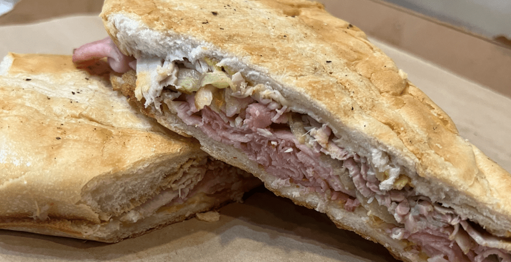 A Cuban sandwich sits on a plate