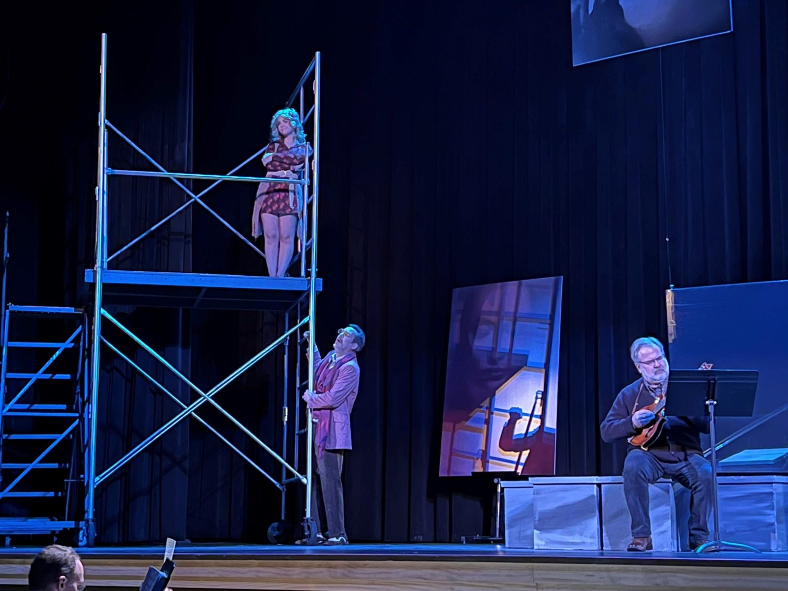 Three actors perform a scene from an opera on a stage