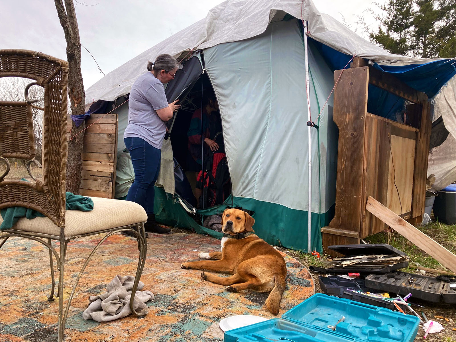 Pastor Christie Love talks with Megan, who is still inside her tent. Megan, along with several other unsheltered people, had to leave the private property on which they were camping on March 23, 2023. Megan said she had lived there for five years.