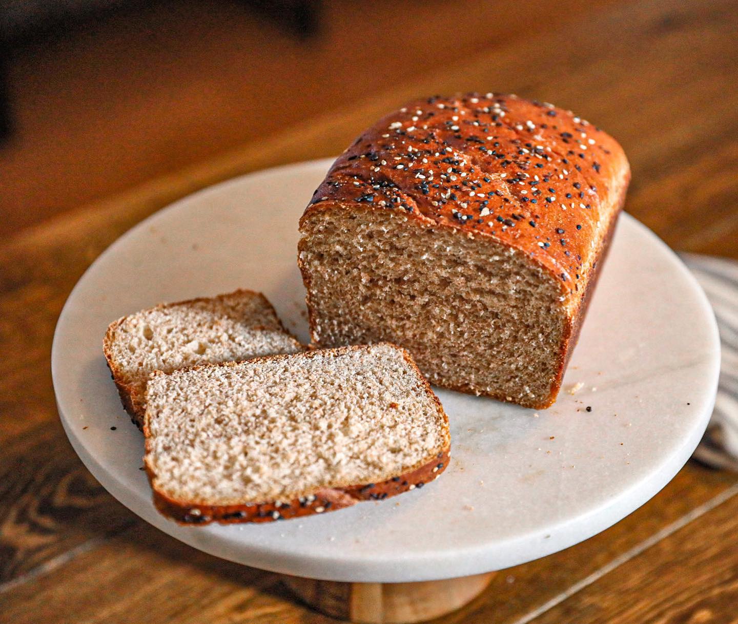 A loaf of bread, with two slices resting next to it, sits on a white plate