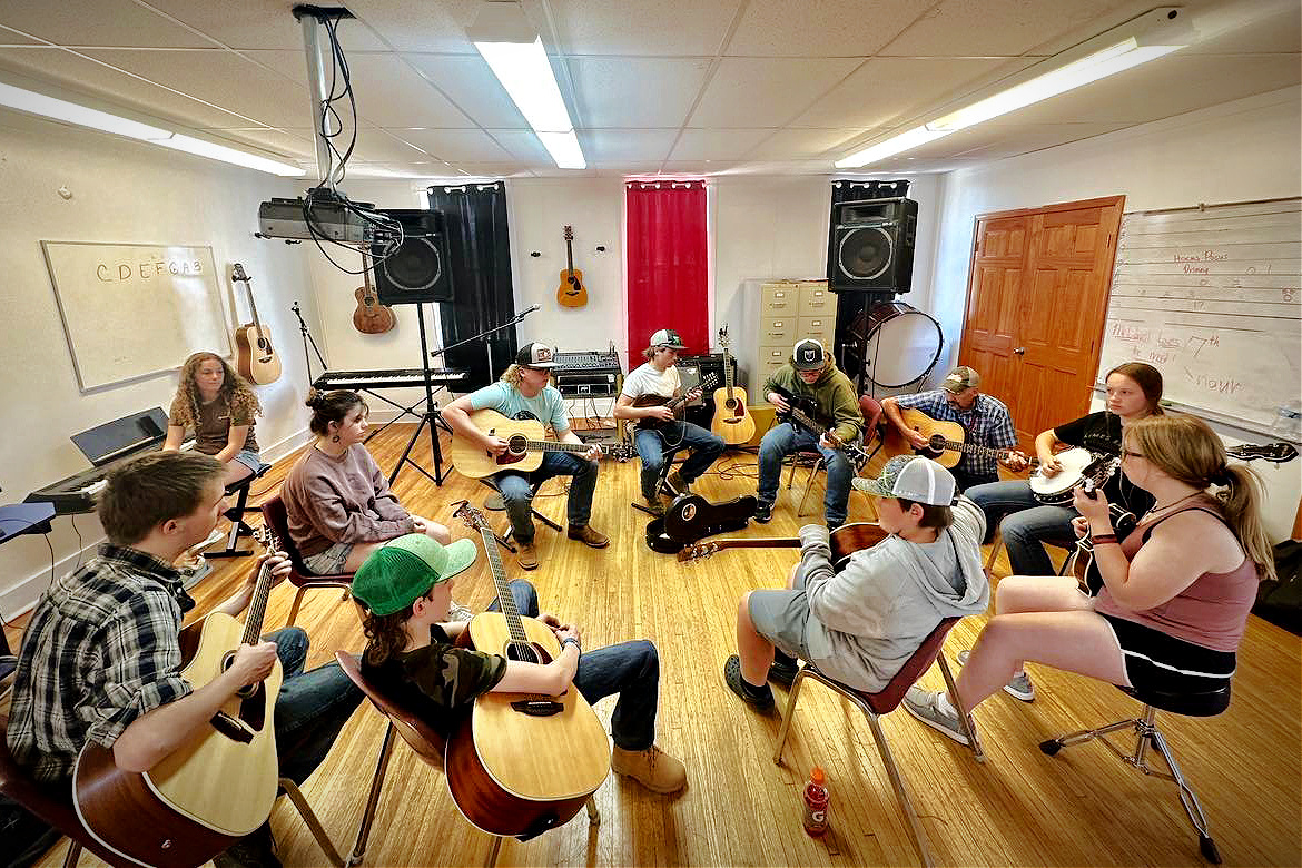 High school students sit in circle with musical instruments