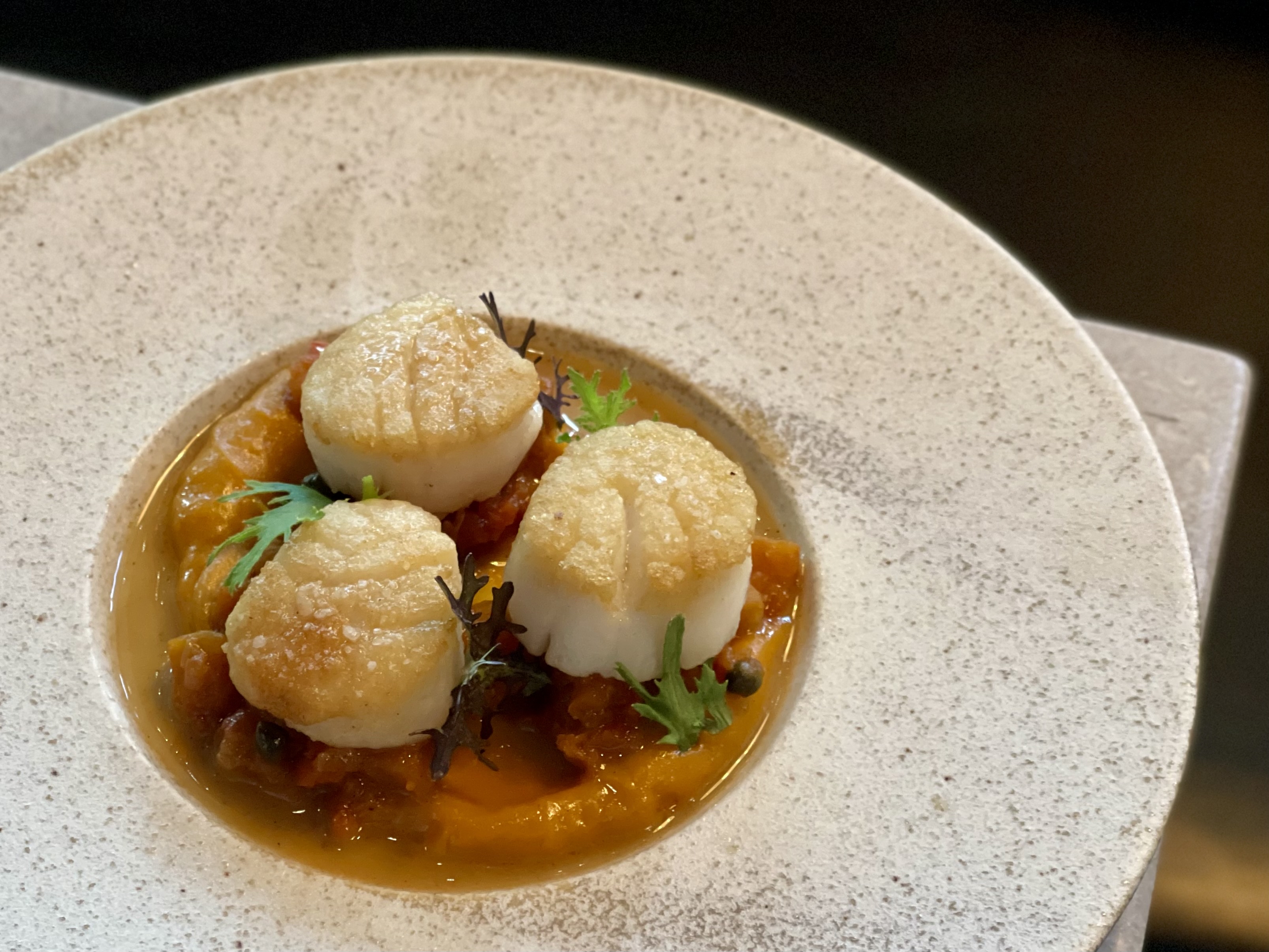 Three scallops sit on a white plate