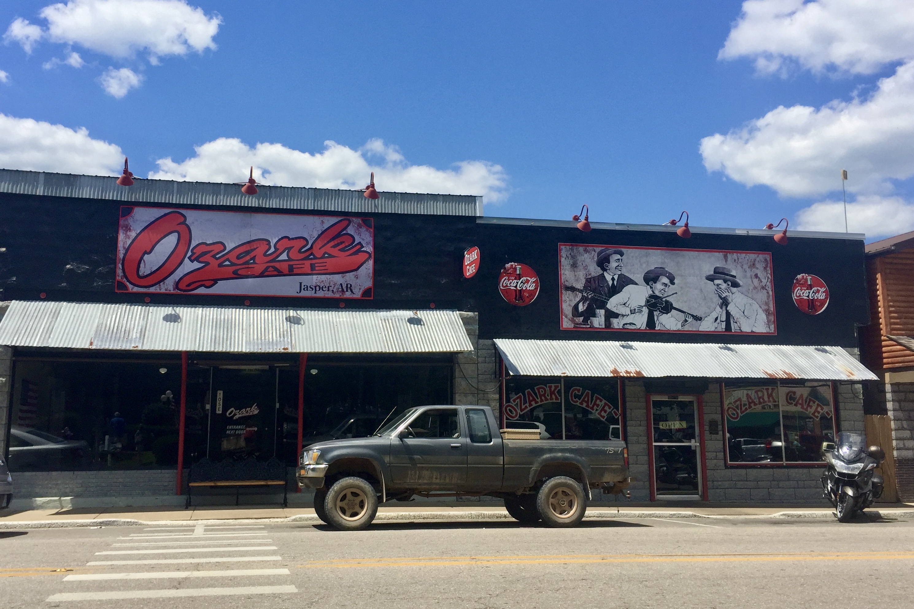 A truck is parked outside a restaurant with a sign reading "Ozark Cafe"