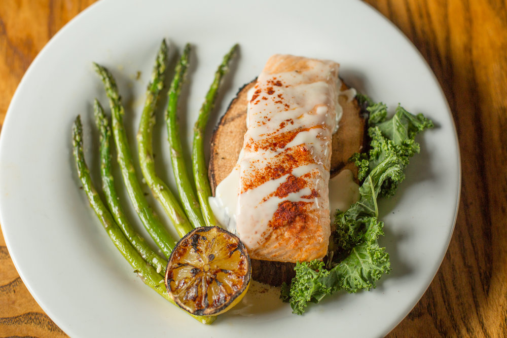 A salmon filet sits on a plate with grilled asparagus