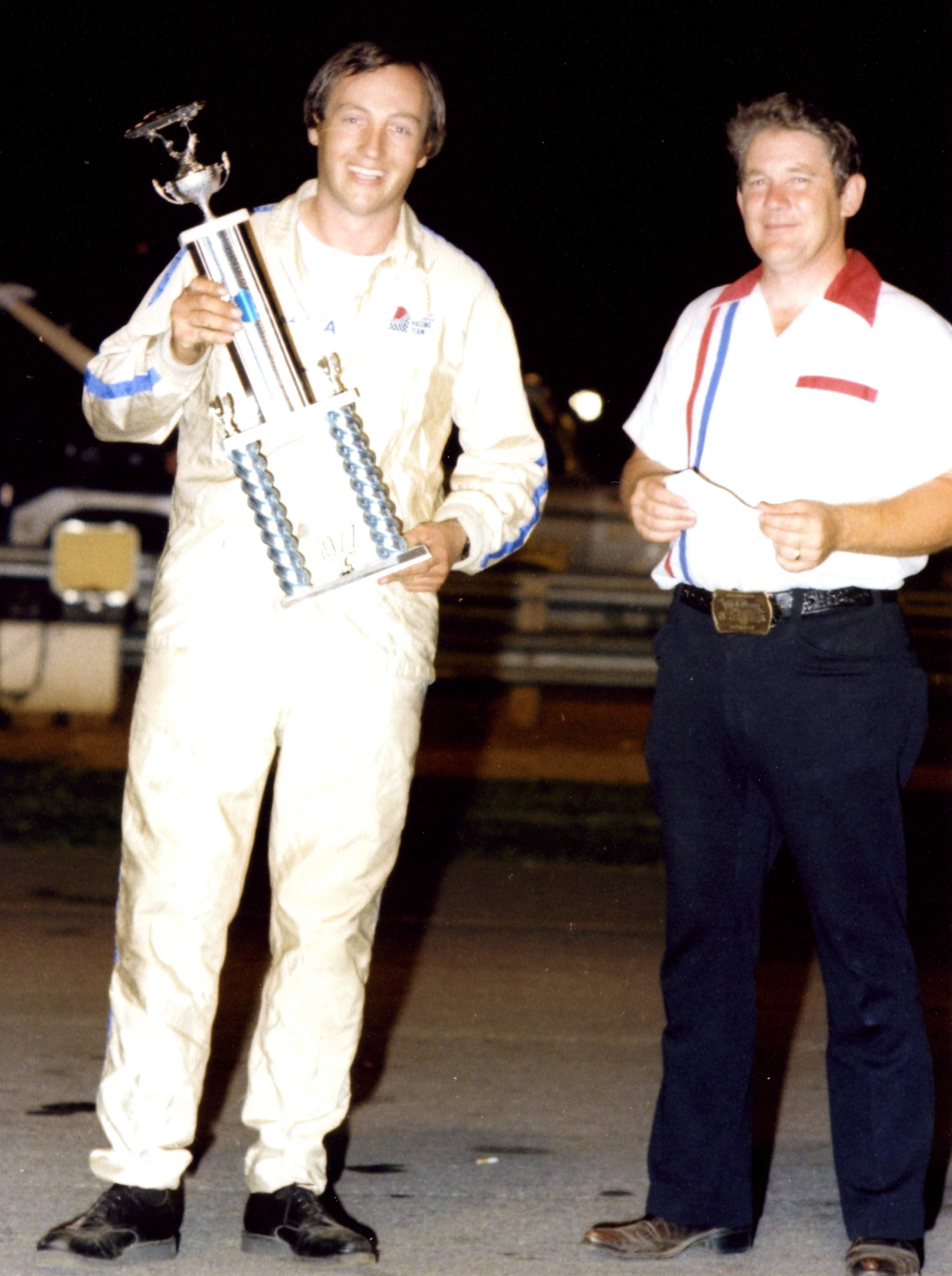 A race car driver is presented a trophy after winning a race