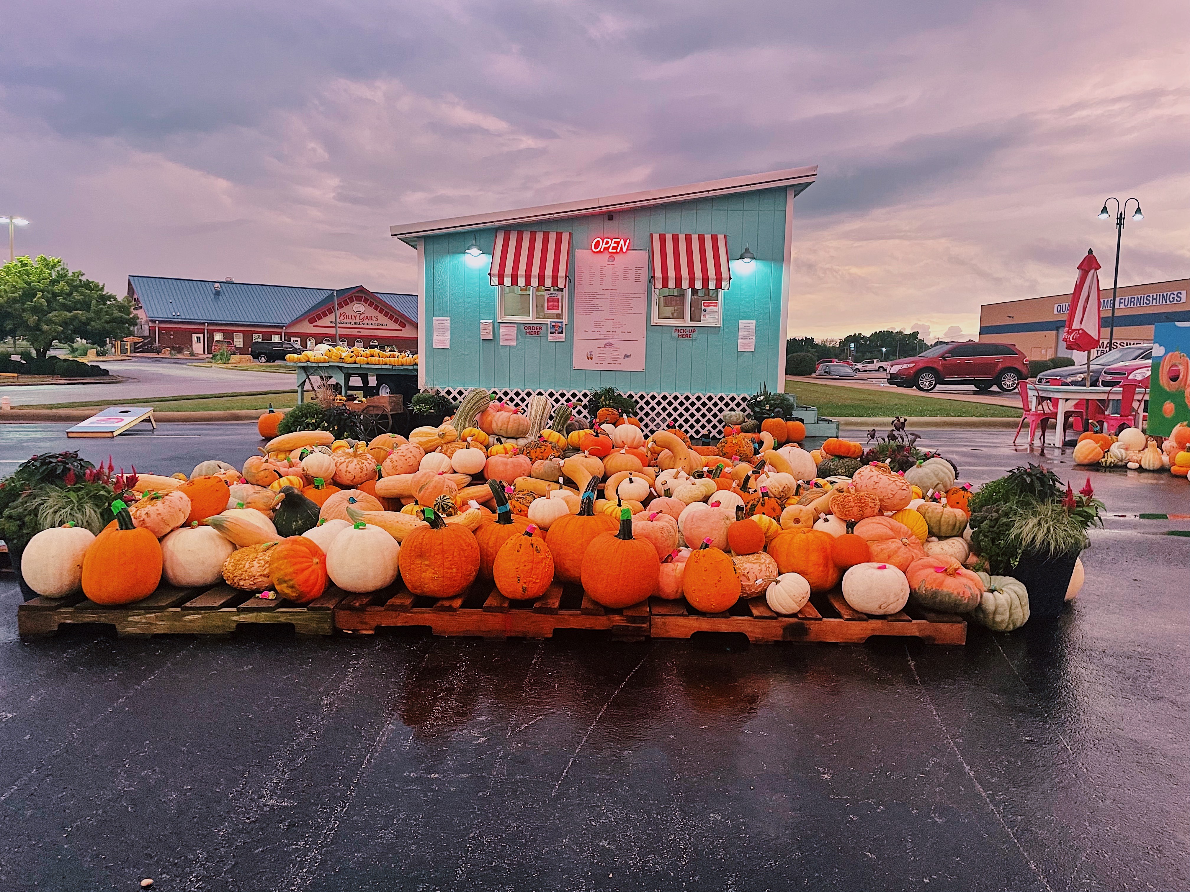 Hundreds of pumpkins sit next to a teal building with red and white striped awnings