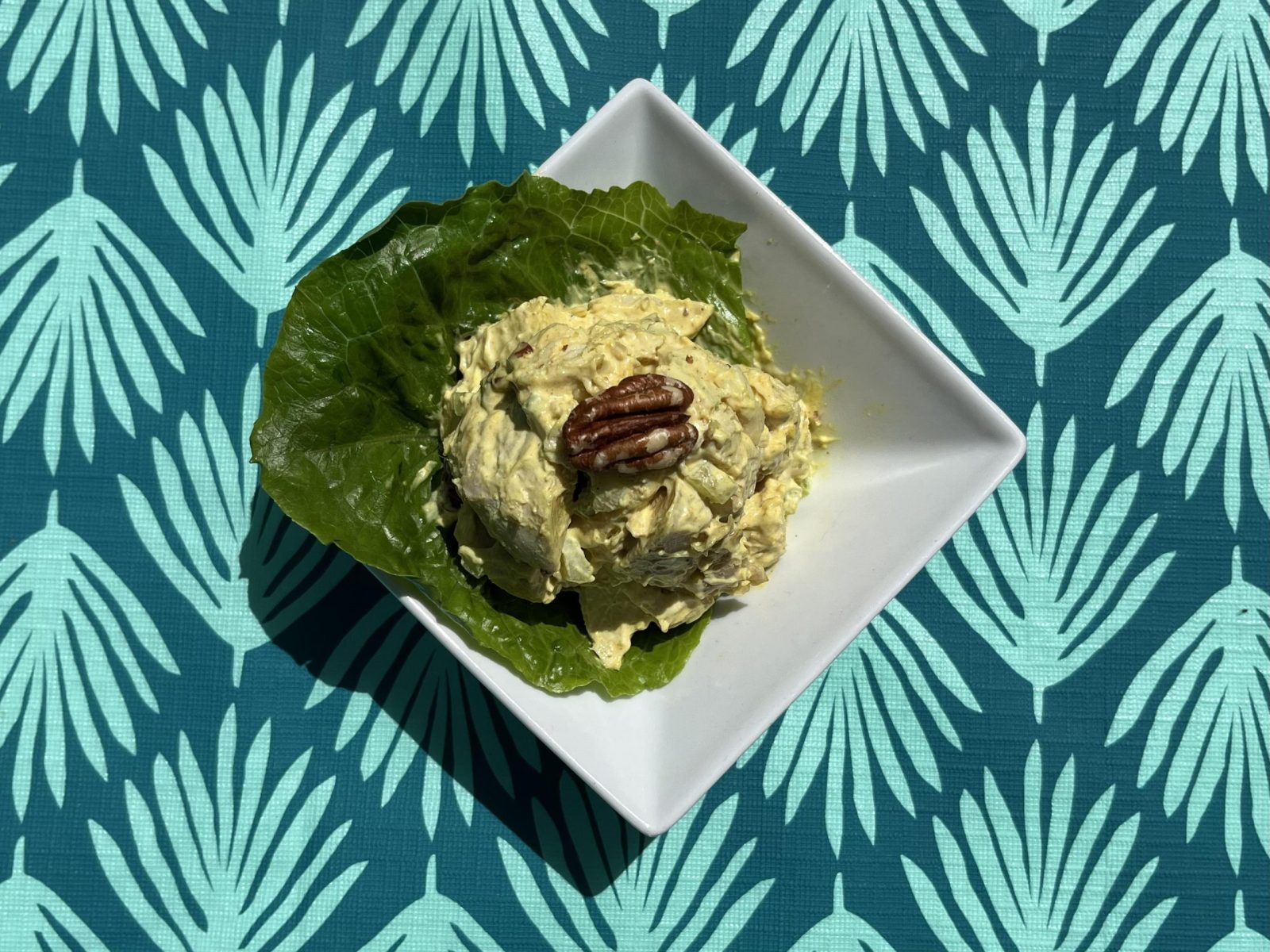 A dish of chicken salad sits on a blue-patterned tablecloth