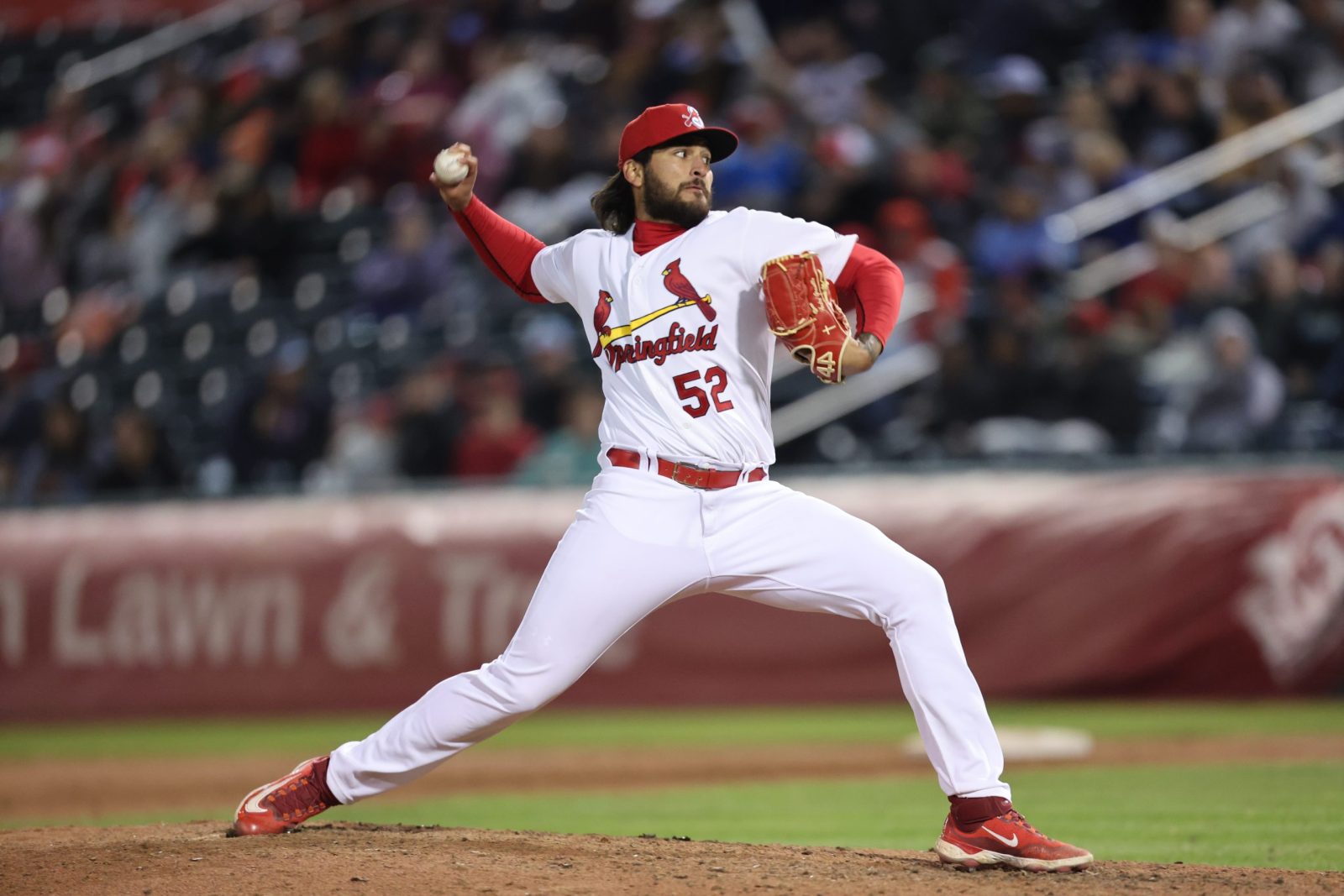 A baseball player wearing a Springfield Cardinals uniform pitches the ball