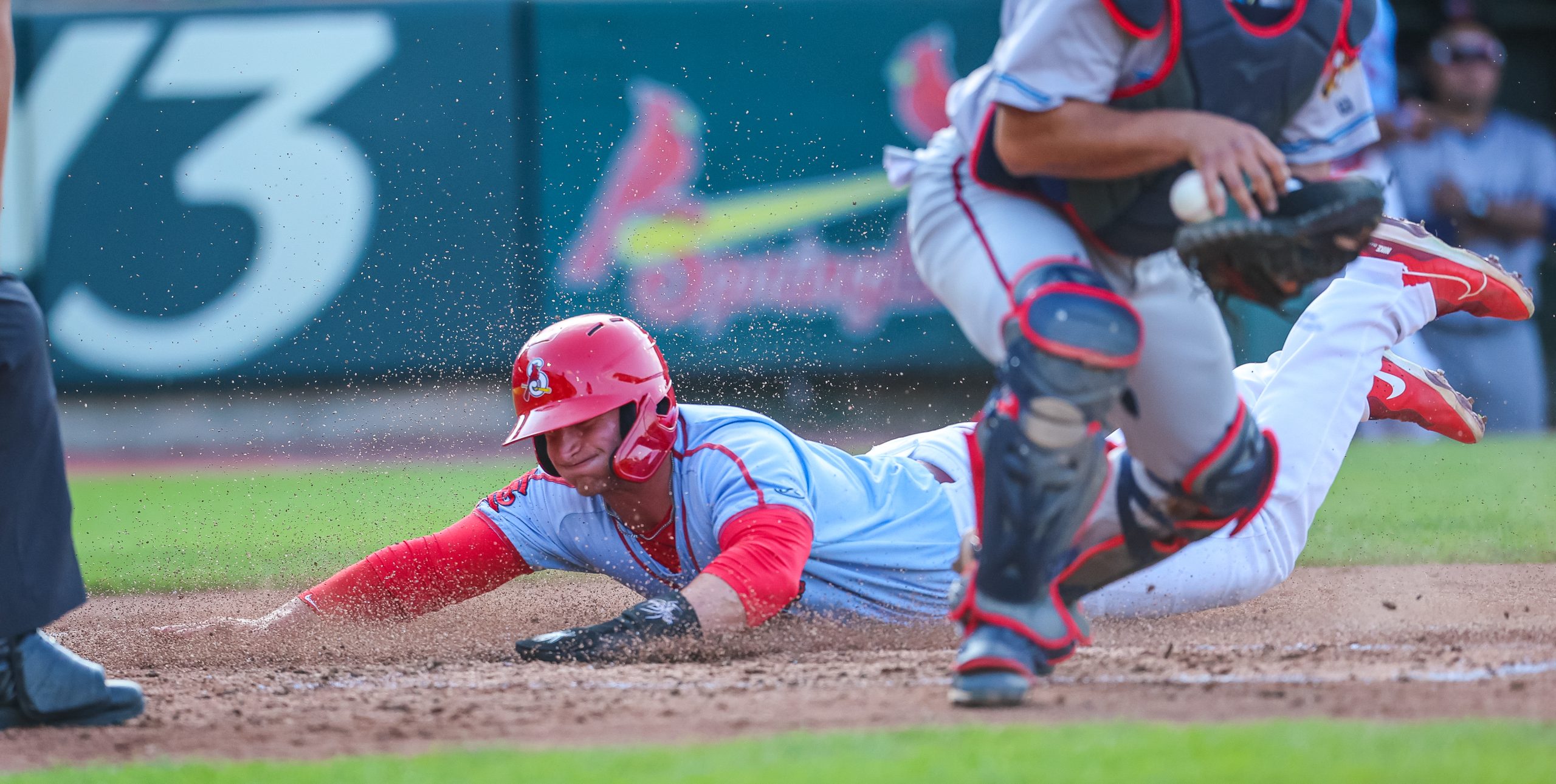 A baseball player in a Springfield Cardinals uniform slides headfirst into home plate