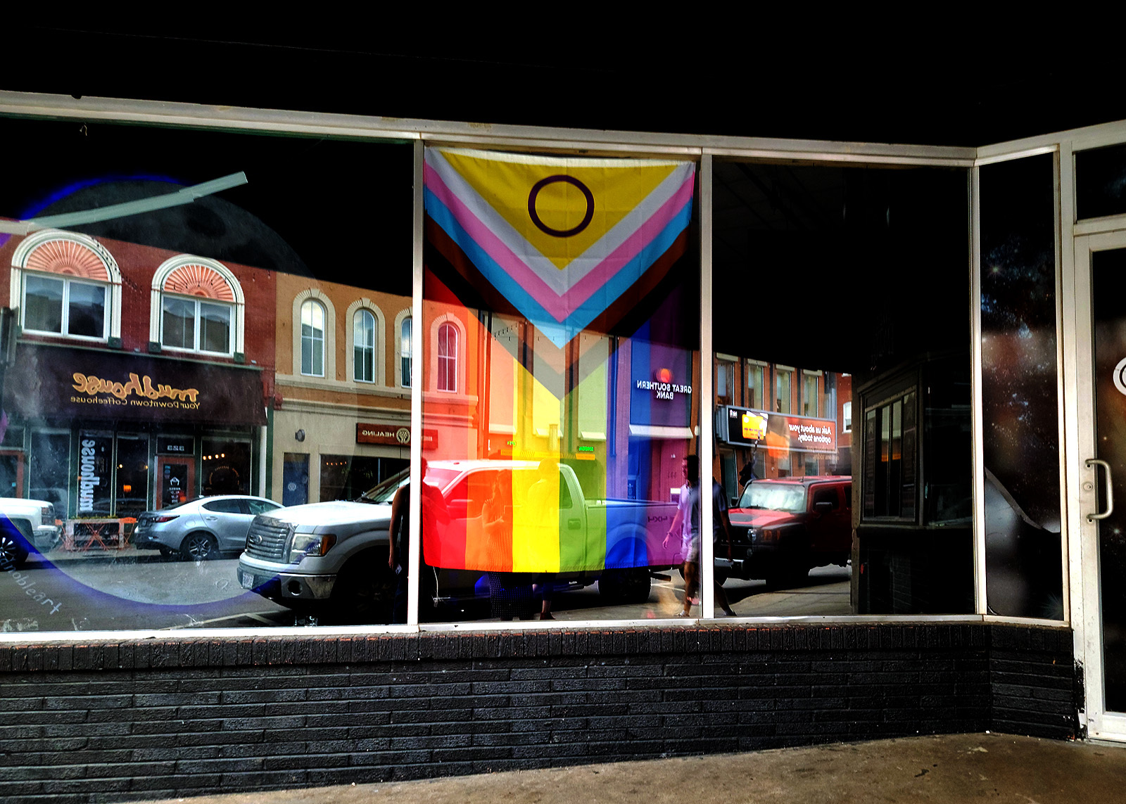 Pride flag hangs inside window of downtown business.
