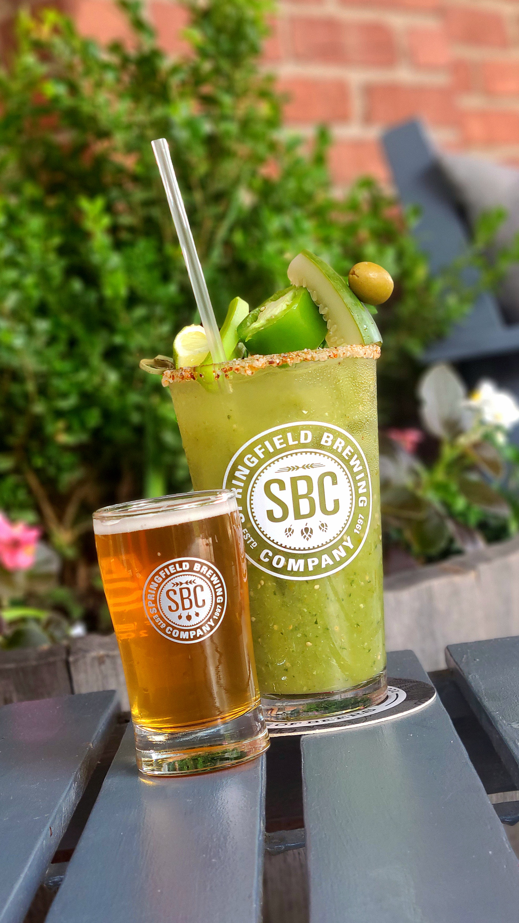 A green Bloody Mary sits on a table, next to a small glass of beer
