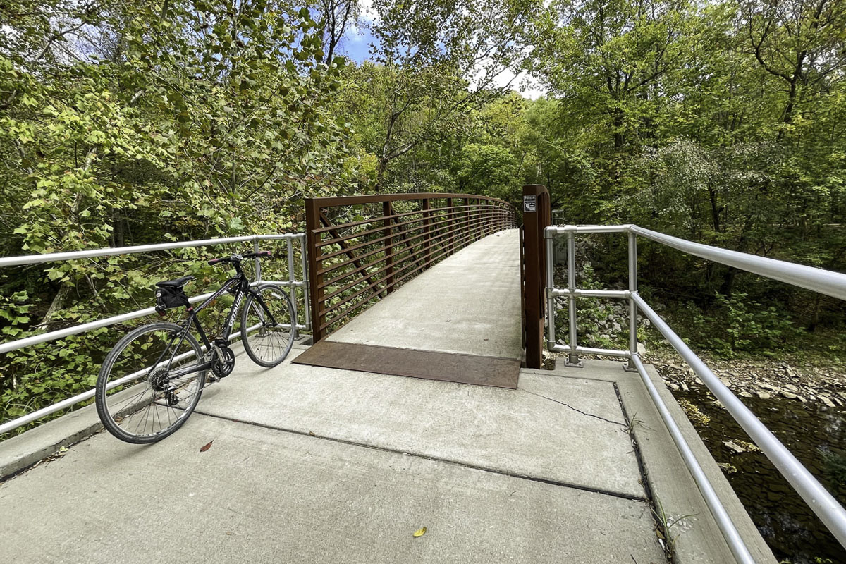 A bicycle sits next to a footbridge on the Fulbright Spring Trail