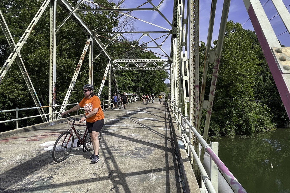 A woman stands next to her bicycle on a bridge over Lake Springfield