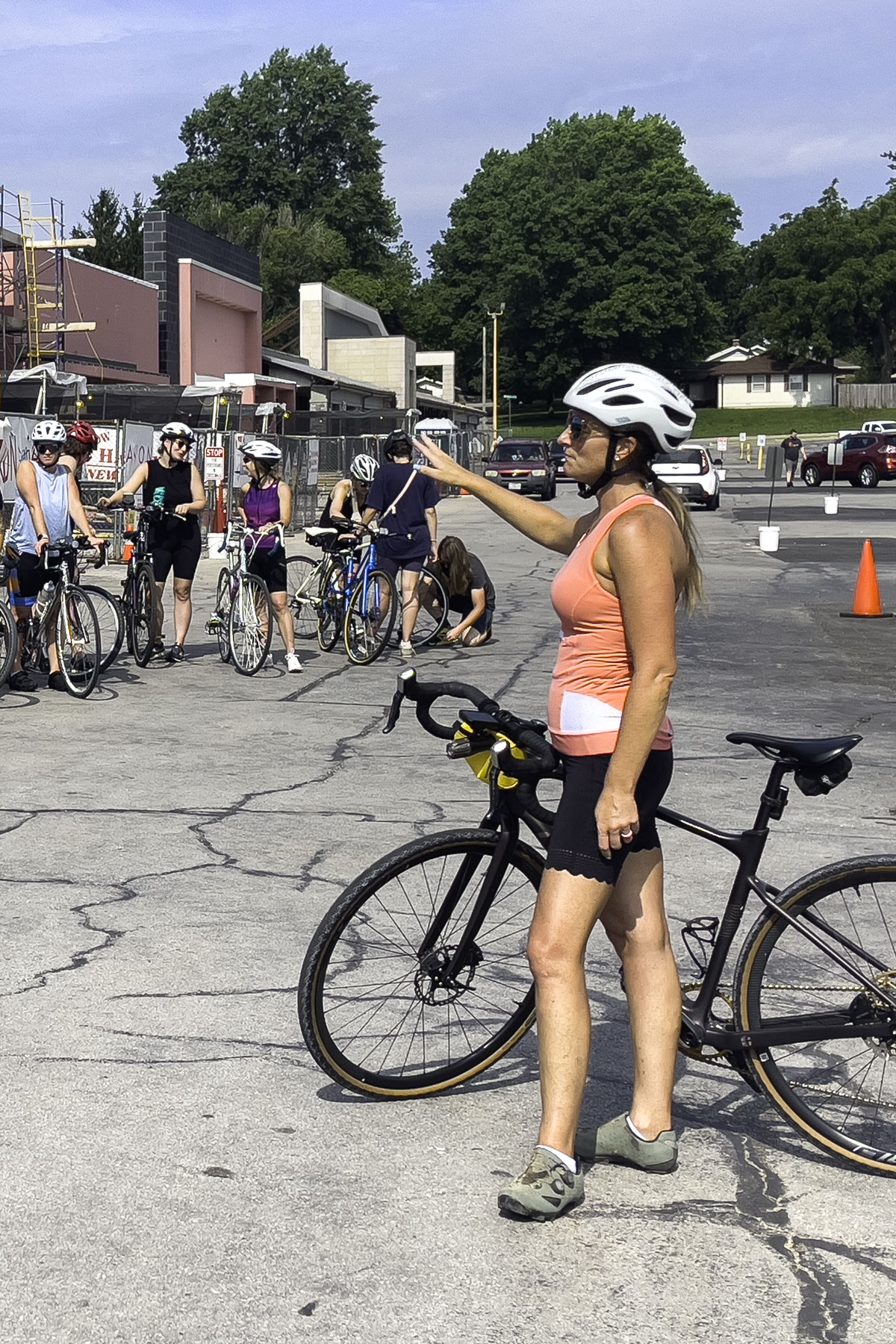 A woman stands next to her bicycle, giving instructions to a group of women on bicycles