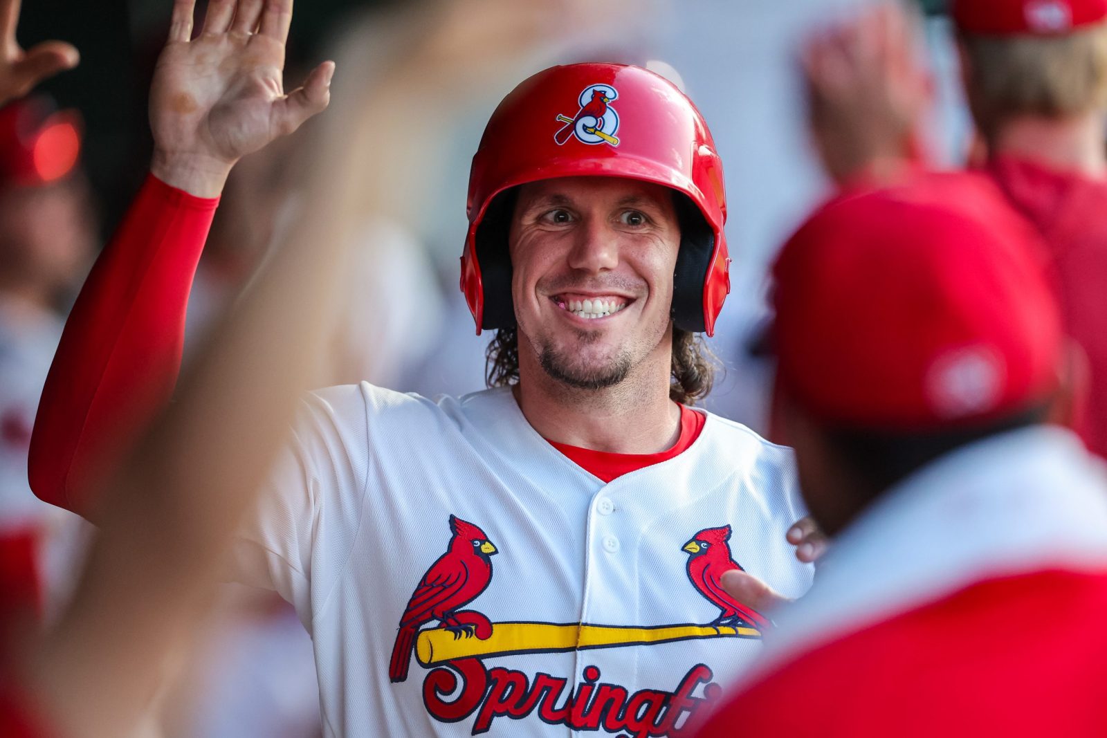 Chandler Redmond, wearing a Springfield Cardinals uniform, high-fives teammates in the dugout