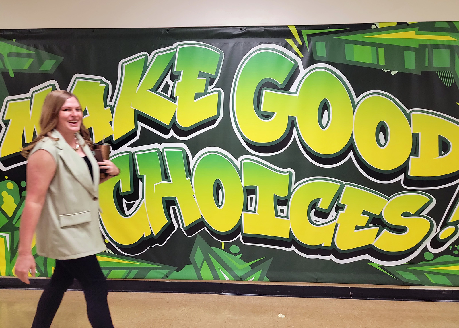 Parkview High School Principal Megan Brown with "Make Good Choices" mural styled like urban graffiti.