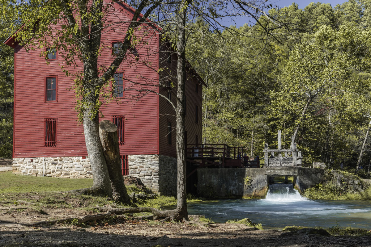 A red mill building sits next to a creek