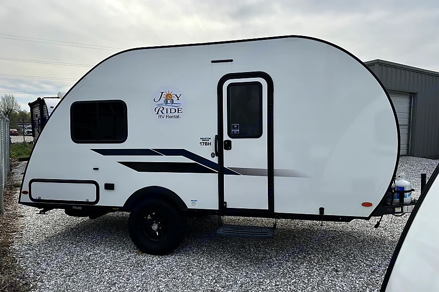 A white camping trailer with the Joyride RV Rentals logo on the side