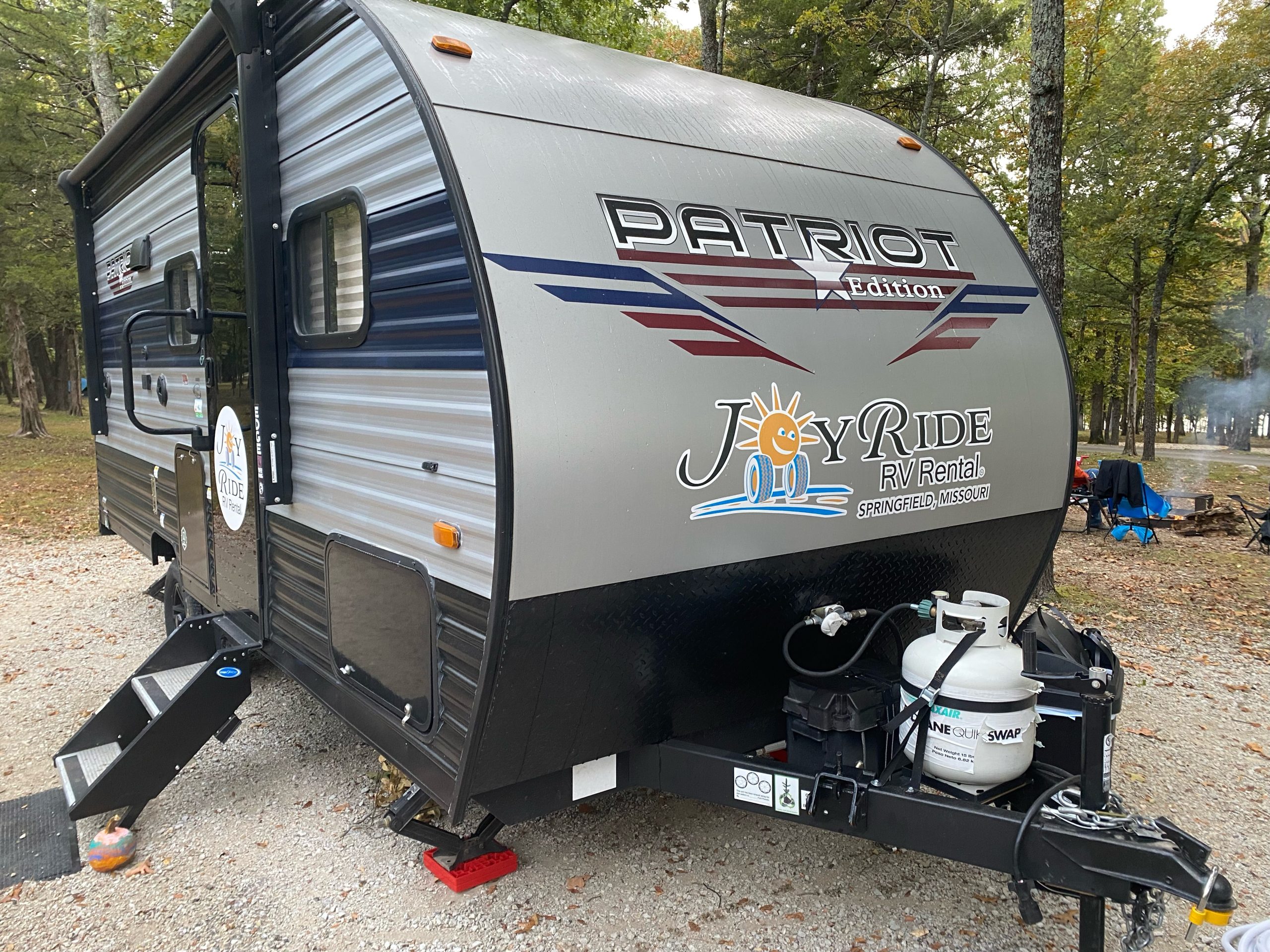 A black, gray and blue trailer with the logo for Joyride RV Rental on its side