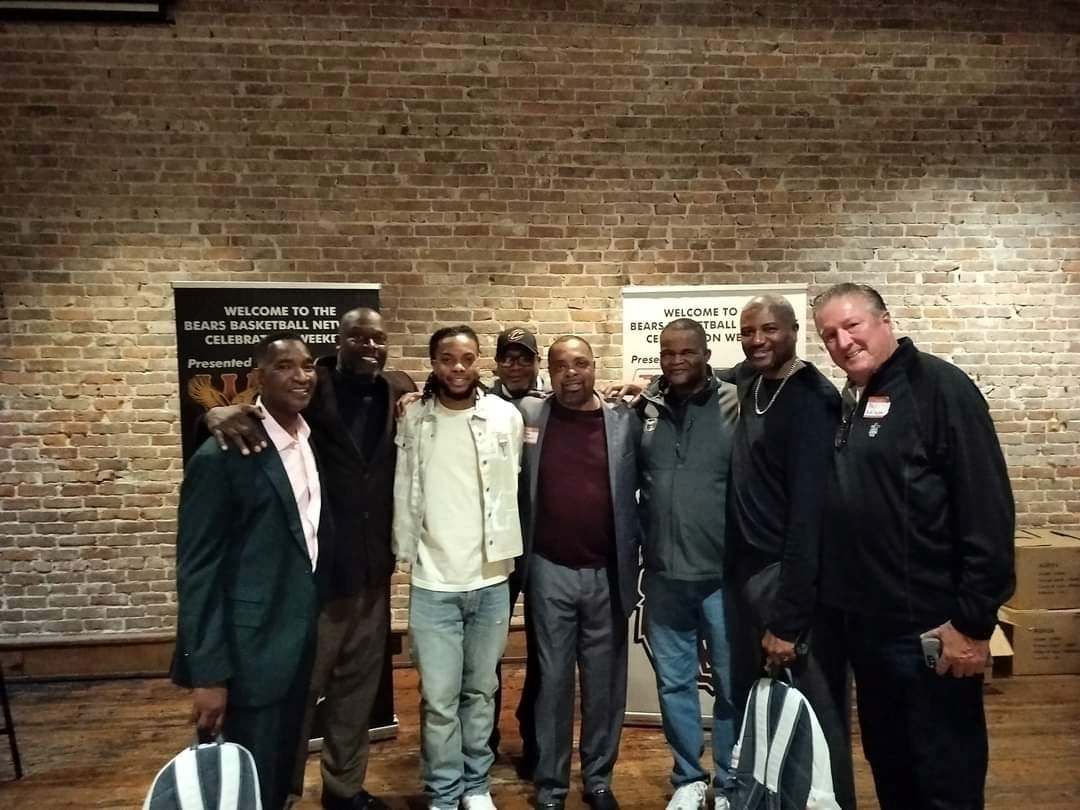 Members of the 1987 Missouri State Bears basketball team pose for a photo in front of a brick wall