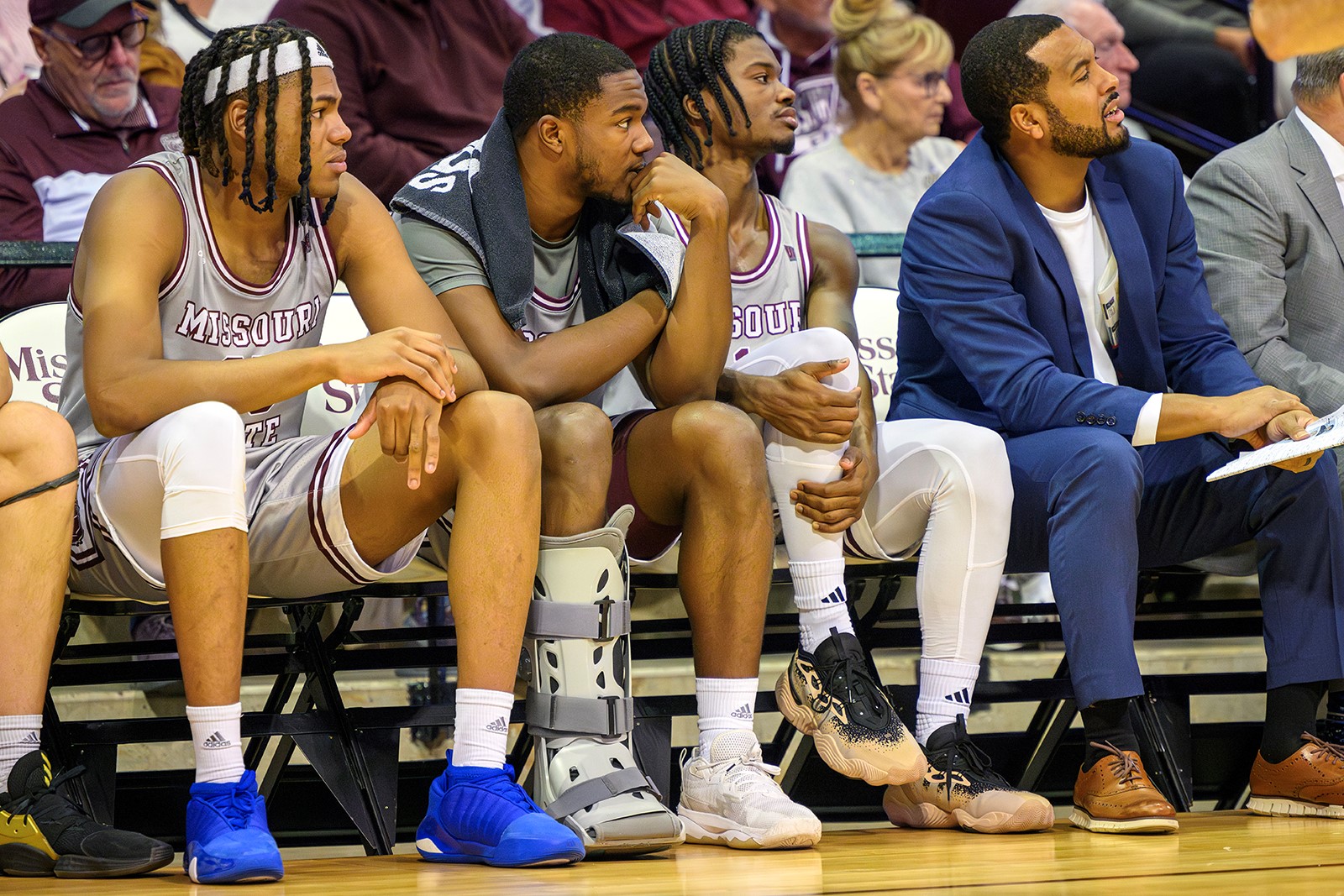 Missouri State Bears basketball players sit on the bench, watching a game