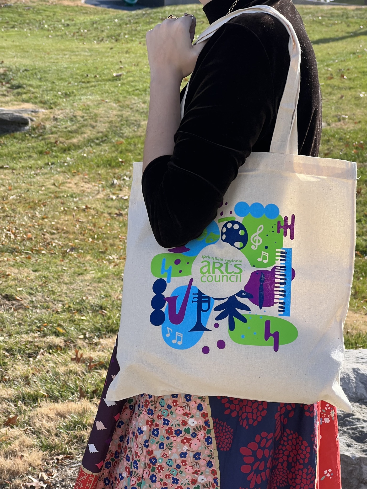 A person wears a canvas tote bag on their left shoulder