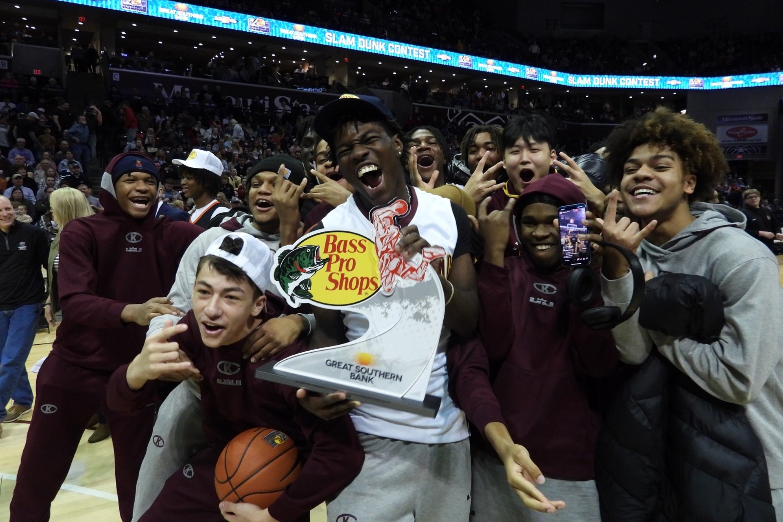 A high school basketball team celebrates after one of their teammates won a slam dunk competition