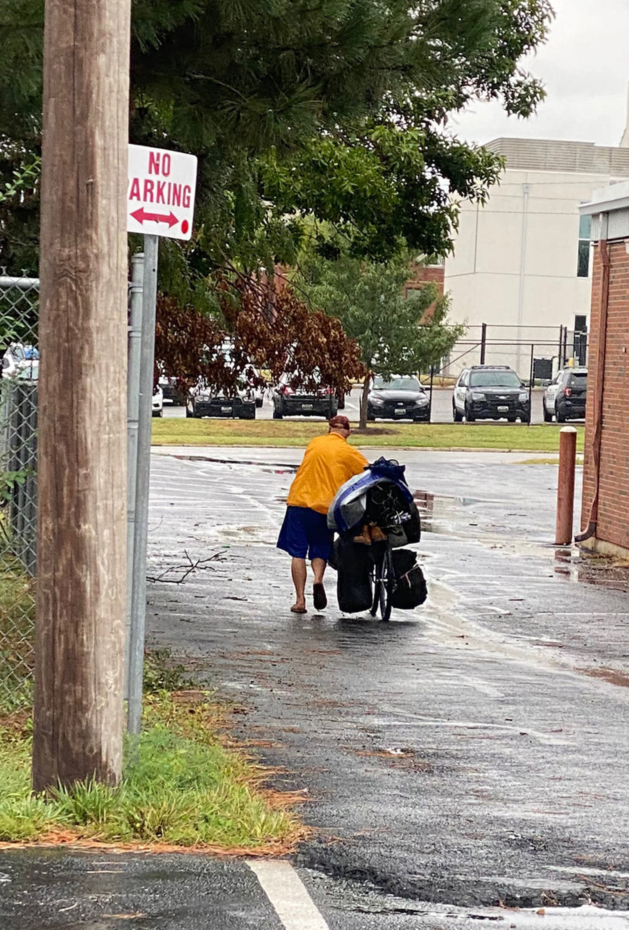 Photo of unsheltered man pushing a bike in the rain
