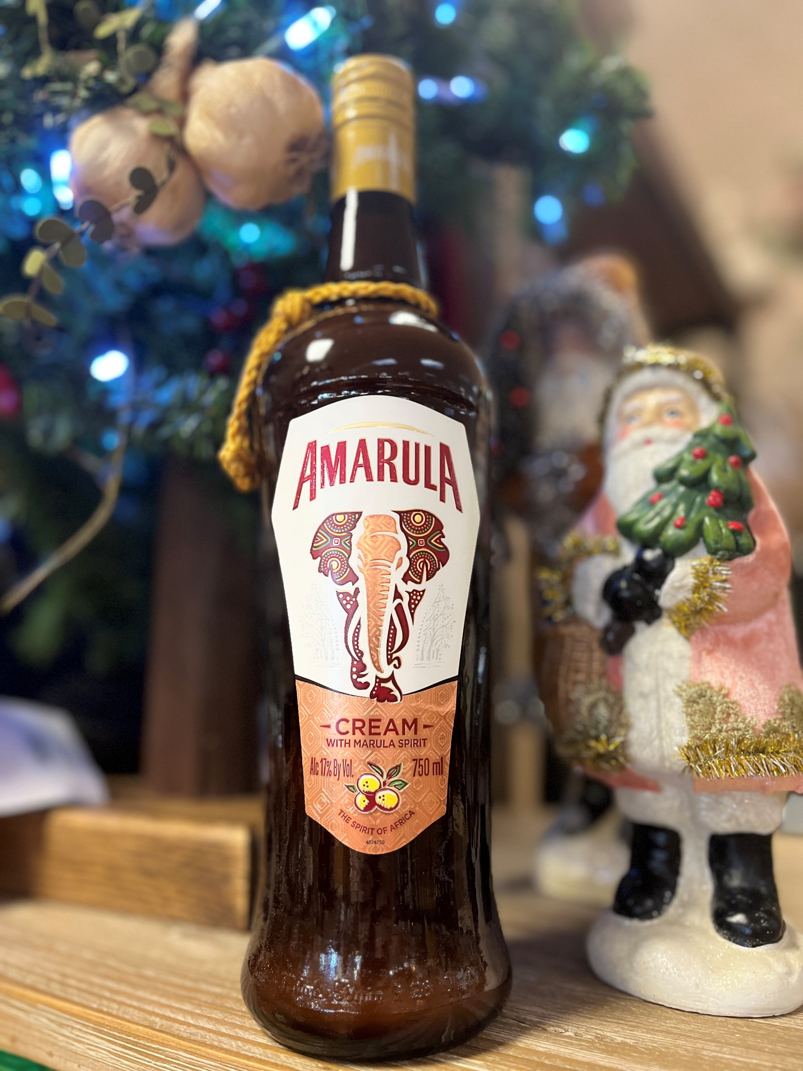 A bottle of Amarula liqueur sits on a table next to a Santa Claus figurine