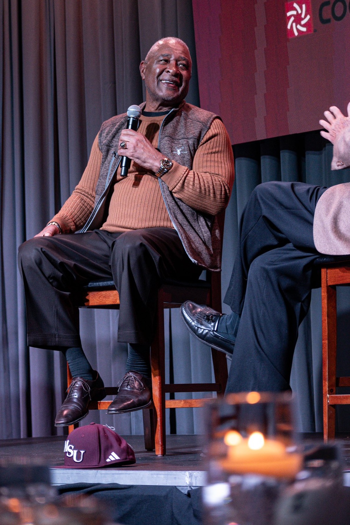 Ozzie Smith, sitting on a stage, smiles while listening to a question.
